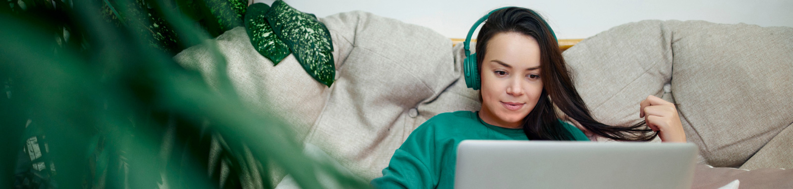 Woman on headphones watching on laptop